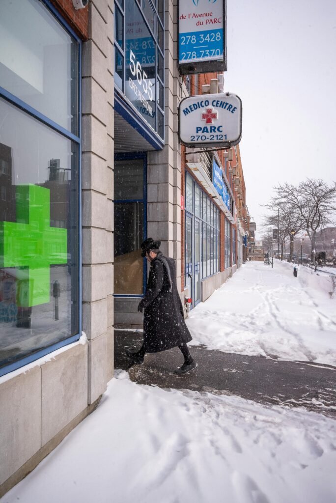 A person walks through a snowy street in Montreal by a medical center.